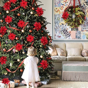 Detail of red glitter poinsettia flowers decorating a Christmas tree in a warm room