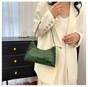 Green crocodile pattern underarm bag shown styled on a model in a minimal indoor setting