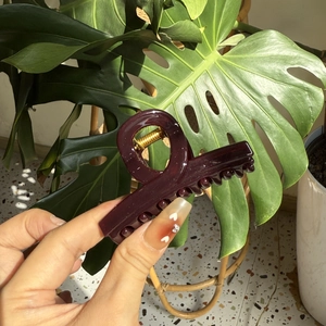 Detail of burgundy glossy hair claw clip with gold metal spring for hair styling