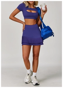 Dettaglio del crop top viola intenso con ritaglio sul petto e gonna a pieghe a vita alta