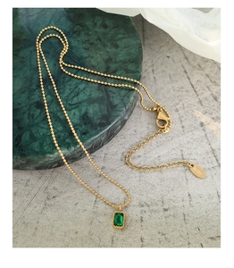 Detail of 18K gold plated emerald zircon necklace with K18 stamp on marble display