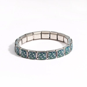 Detail of stainless steel modular charm bracelet with green and blue floral enamel pattern