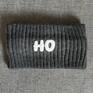 Close-up of dark grey ribbed knit headband featuring a white HO letter patch detail