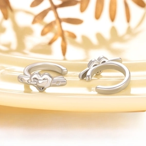 Detail of heart belt buckle ear cuff in silver metal on a minimalist ceramic plate