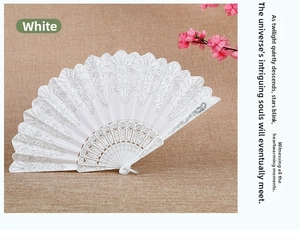 Detail of white lace folding fan with sequins and intricate vintage hollow carvings