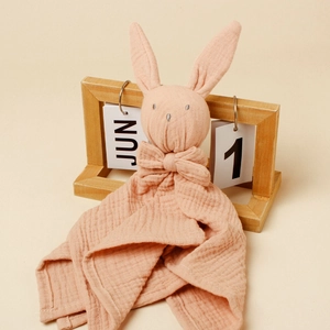 Pink bunny baby comforter made of soft double-layer cotton muslin on a warm background