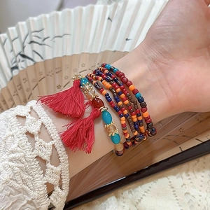 Close-up of bohemian multilayer beaded bracelet with red tassel and turquoise stones