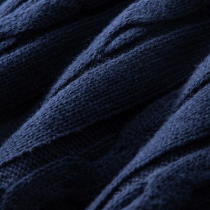 Macro shot of navy blue cable knit texture on a premium cotton crew neck sweater