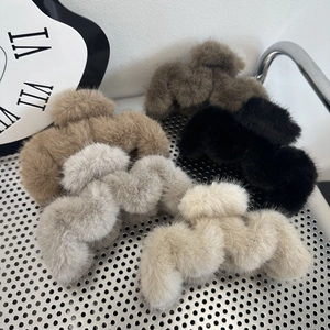 Detailed view of five plush hair claw clips in beige, grey, black, and cream colors