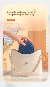 Deep blue round mini jewelry box being placed into an elegant white handbag