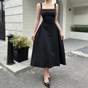 Outdoor shot of a black mid-length dress with pleated waist and elegant A-line silhouette