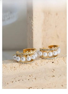 Vue macro de boucles d'oreilles en C dorées avec rangées de perles et cristaux brillants