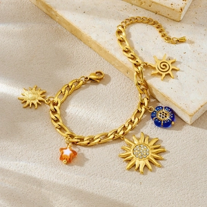 Gold-plated chunky chain bracelet with sun, star, and acrylic charms on textured stone
