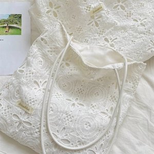 Close-up of the delicate floral lace texture and brand label on a beige tote bag