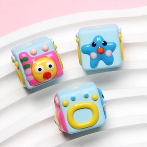 Macro shot of blue acrylic cat paw beads with cute resin chicks, stars and letters