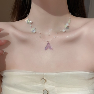 Detail of fishtail pearl necklace with iridescent shell charms on a female model