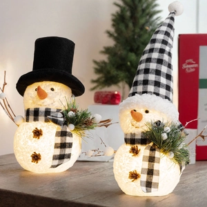 Lighted Christmas snowman figurines with pointed hat and pine cone details in warm glow