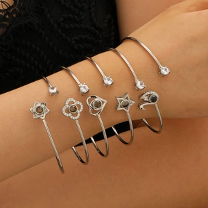 Détail de cinq bracelets de projection en argent avec breloques cœur, étoile et fleur