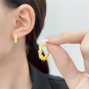 Detailed close-up of gold hoop earrings with a textured crushed gold finish for women