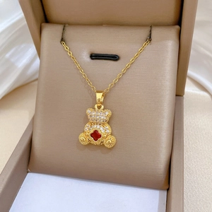 Close-up of a gold titanium necklace featuring a bear pendant with red clover and zircons