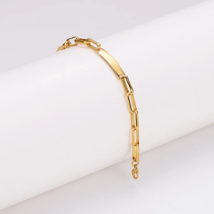 Minimalistisches goldenes Edelstahl-Armband auf einer weißen zylindrischen Stütze