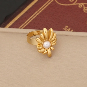 Macro shot of gold flower ring featuring a center pearl accent on a soft beige surface