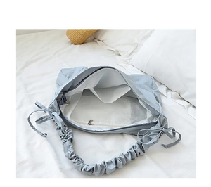 Detail view of the spacious interior with zipper pocket and pleated strap on canvas bag