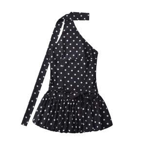 Détail d'une robe à pois noire et blanche à une épaule avec ourlet bulle et nœud à la taille