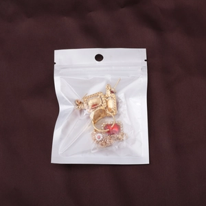Detailed view of a gold jewelry set with red and white gemstones on brown satin fabric
