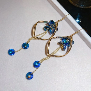 Dettaglio macro di orecchini a nappa dorati con cristalli blu in una scatola portagioie