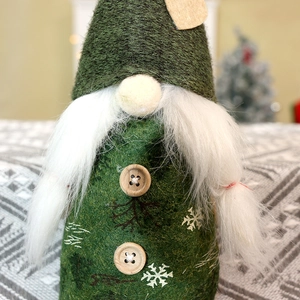 Dettaglio dello gnomo di Natale verde bosco con doppi bottoni in legno e motivi a fiocchi