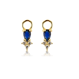 Detail of gold earrings with blue pear-cut gemstone and clear stones on white background