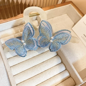 Detailed view of lace butterfly hair claw with cream finish and pearl accents