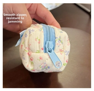 Close-up of mini floral quilted makeup bag with smooth sky blue zipper detail