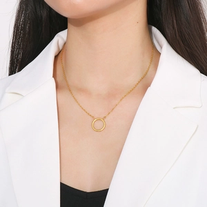 Detail of minimalist interlocking gold circles necklace worn on a model with white blazer