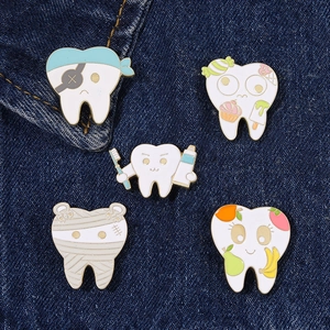Detailed view of five creative tooth enamel pins on denim fabric showcasing funny designs