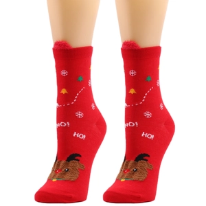Detail of red knitted Christmas socks with 3D reindeer patch and snowflake patterns