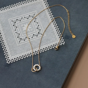 Gold titanium steel double ring necklace with pearl pendant on a lace background
