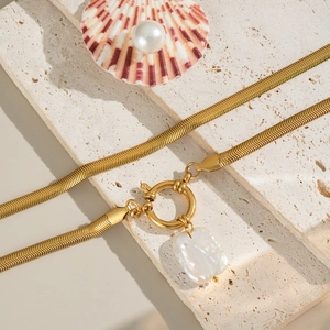 Collier chaîne serpent dorée avec perle baroque et fermoir OT sur fond de pierre naturelle