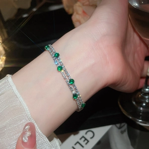 Close-up of 18k gold plated double-layer bracelet with green and clear zircons.