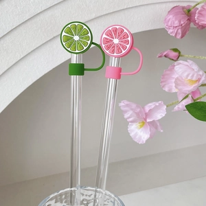 Food-grade lime and grapefruit silicone straw covers for glass straws on white background