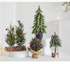 Detail of diverse mini Christmas trees with pine cones, red berries and snow on wood bases