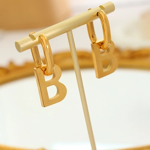 Statement gold-plated letter B drop earring on stand with minimalist geometric design