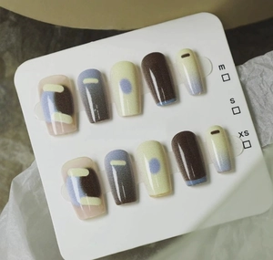 Detail of matte press-on nails featuring hand-painted chocolate and cream geometric designs