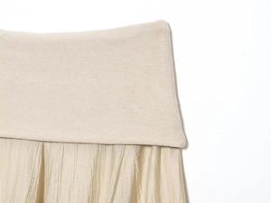 Detail der beige plissierten Rock-Taille mit Rippstrick-Naht und weicher Textur