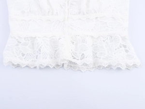 Detailed close-up of white floral lace texture with buttons and scalloped hemline