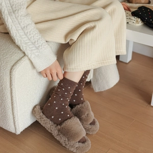 Detail showing knitted wool socks with polka dots and fuzzy slippers in a cozy winter setting