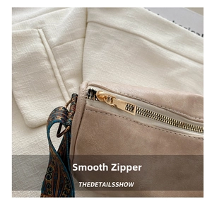 Macro shot of smooth gold-tone metal zipper on a beige Boston bag with printed strap