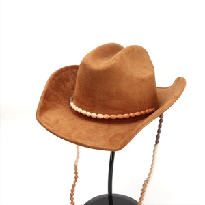 Détail d'un chapeau de cowboy en daim marron avec ruban perlé ethnique et glands