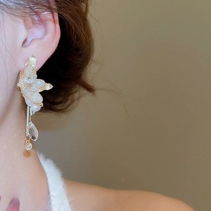 Close-up of golden butterfly wing earrings with long tassels on female model
